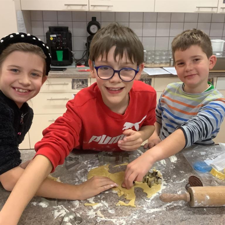 Kinder mit Teig an einer Küchenarbeitsplatte
