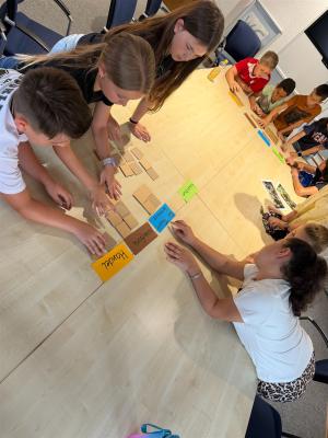 Eine Gruppe von Jugendlichen sitzt um einen Tisch und nimmt gemeinsam an einer Aktivität teil.